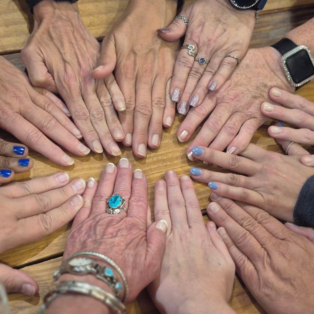 Women's hands gathered together in a circle of connection