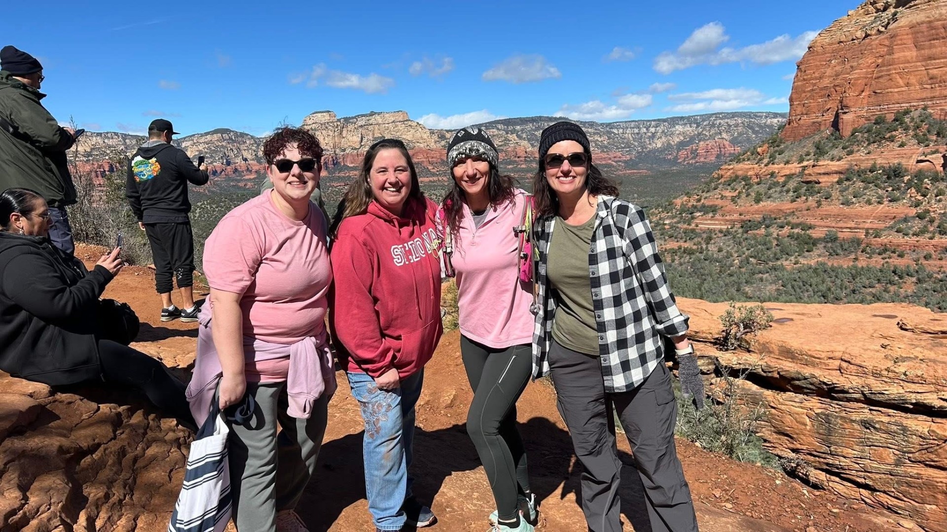 Four women together overlooking Sedona red rocks, laughing and connecting